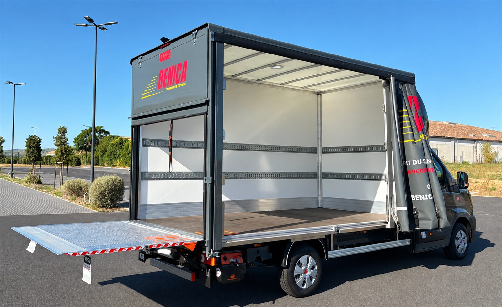 La camionnette BENICA, bâche latérale ouverte sur toute la longueur, hayon déployé